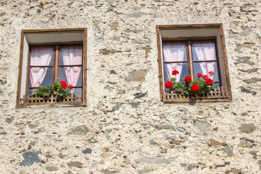 Old building with red flowers in windows - facade with old window, Austria