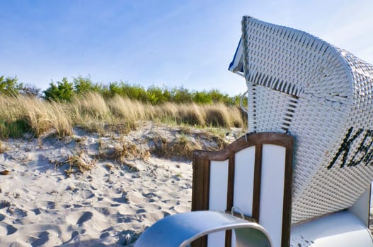 Beach chair on the beach of the Baltic Sea in Zingst. Sun, blue sky. Dune in the background with dune grass. Landscape shot from German coast