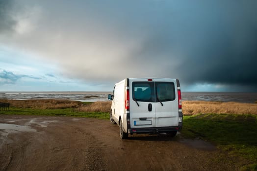 Camper van driving next to the wadden sea at low tide, traveling at the beach of Romo in Denmark, adventure vacation und lifestyle
