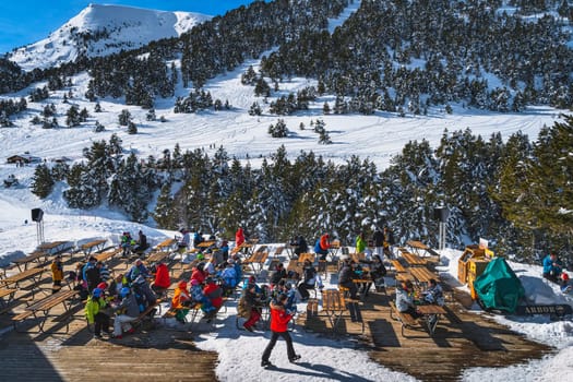 El Tarter, Andorra, Jan 2020 People sitting at the tables relaxing and eating with a beautiful view on snowy mountains and forest. Winter ski holidays
