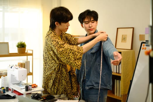 Young fashion designers working on a clothing project in stylish studio.