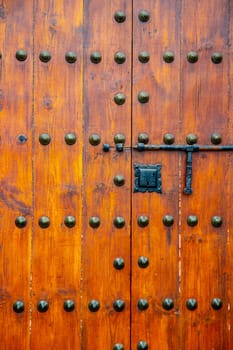 Detail from old massive large wooden door in a stone wall of a church.