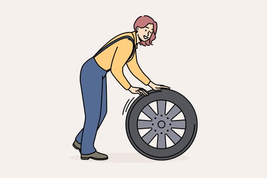 Smiling female mechanic with car tire working at auto repair service. Happy woman engineer busy with wheel repairing automobile. Vector illustration.
