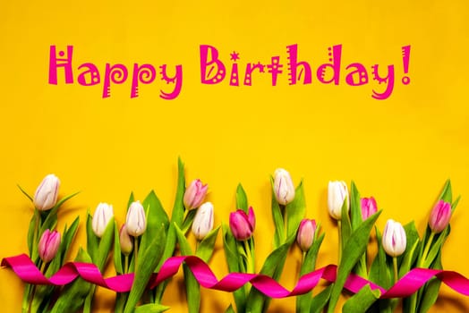 English Text Happy Birthday. White And Pink Tulip Spring Flowers With Ribbon. Yellow Wooden Background