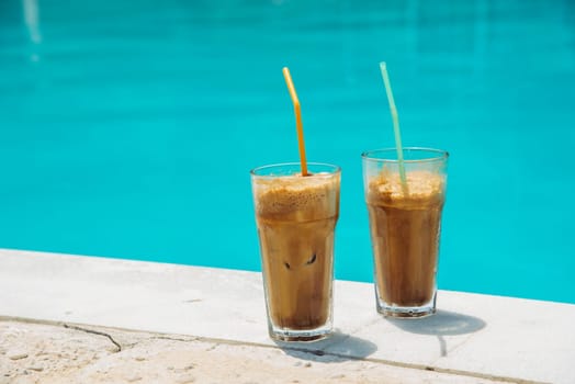 Two glass of iced frappe near the swimming pool.