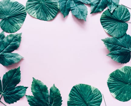 Dark green leaves frame over pastel pink from above. Trendy social media minimal background with nature foliage border. Top view. Girly modern and clean banner for fashion and beauty.