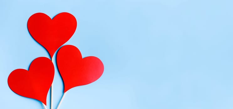 Red valentine hearts on pastel blue background from above. Valentine's day celebration banner. Creative minimal love concept. Hearts balloons top view. Valentine pop art colorful simple design layout.