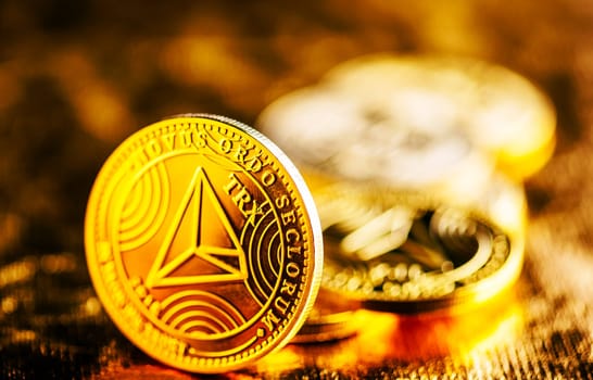 Closeup of golden tron coin TRX cryptocurrency over black and gold background. Virtual money altcoin and blockchain concept.