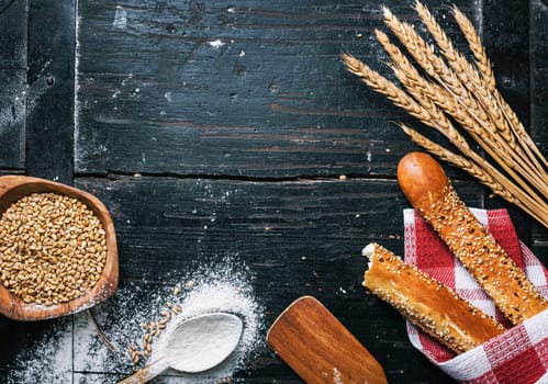 Fresh french baguette bread, organic flour and wholegrain wheat on dark vintage wooden board form above. Top view of traditional baked bread. Bakery shop menu background.