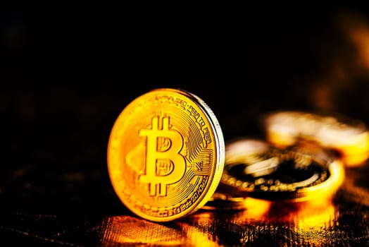 Closeup of golden bitcoin BTC cryptocurrency over black and gold background. Virtual money and blockchain concept.