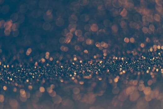Blur neon gold and blue light circle background. Sparkling firework bokeh dots in vintage film filter style. Luxury and classy new year and christmas celebration party textured dark backdrop. Blurry golden dust particles.