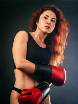 Beautiful woman with long red hair wearing boxing gloves and sportswear.