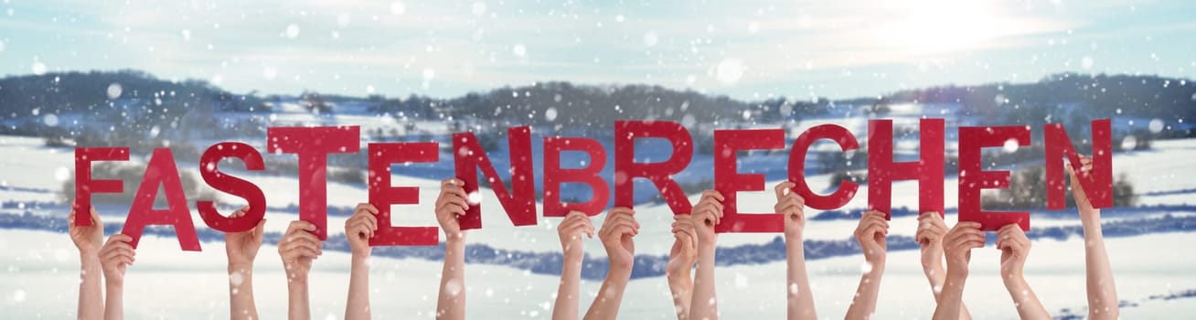 People Hands Holding Red German Word Fastenbrechen Means Fast-Breaking. Snowy Winter Background With Snowflakes