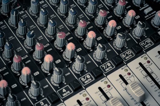 Closeup and detail of audio mixing console with faders and knobs. used for audio production