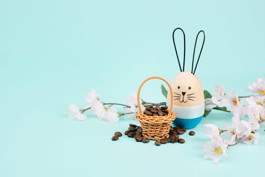 Wicker basket with roasted coffee beans, an easter bunny and cherry blossom, greeting card holiday, spring season
