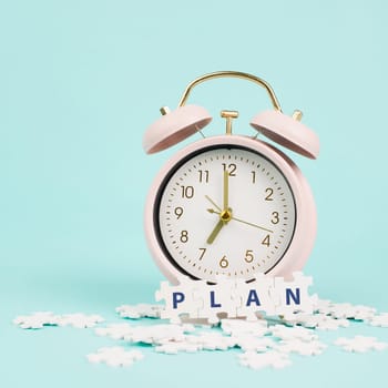 Alarm clock with the word plan standing on puzzle pieces, brainstorming for new ideas, planning new goals and resolutions