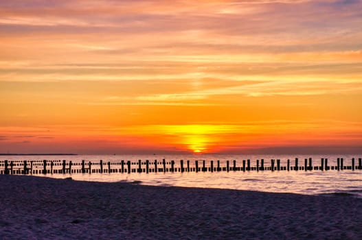 At sunset, the groynes jut into the sea. The sun shines on the Baltic Sea. Landscape from the coast