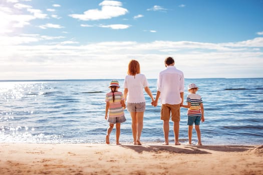 Mother and father with their children standing on the beach on the resort. Concept of the family vacation and tourism.