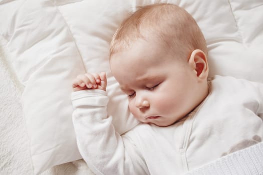 Cute five month old baby sleeping in comfortable bed. Concept of the family andparenting.