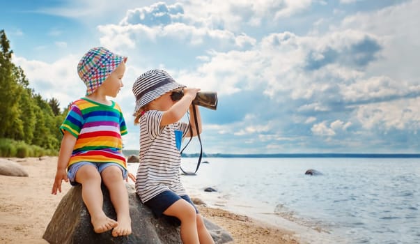 Two children sitting on the stone on the seacoast in summer. Concept of the family vacation and tourism.