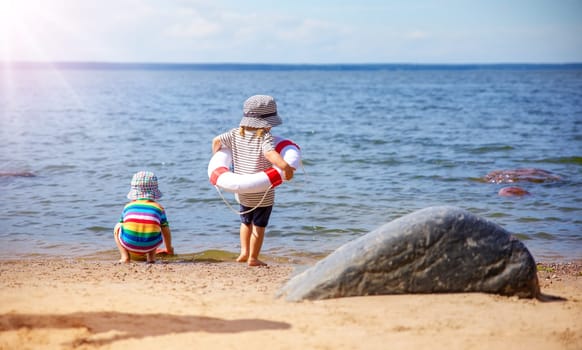 Girl and boy playing on the seashore with Lifebuoy. Concept of the family vacation, childhood and friendship.