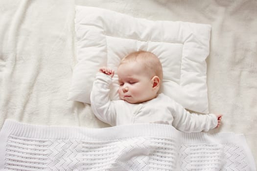 Cute five month old baby sleeping in comfortable bed. Concept of the family andparenting.