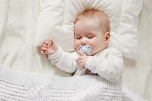 Cute five month old baby sleeping in comfortable bed. Concept of the family andparenting.