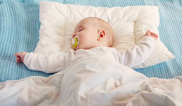 Cute three month old baby sleeping in comfortable bed. Concept of the family andparenting.