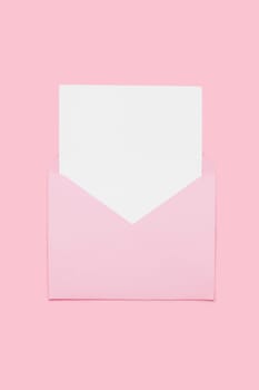 Closeup on blank empty white paper card in pink opened envelope isolated on pink pastel color background. Love letter minimal concept. Conceptual layout template with text place on postcard. Mock-up