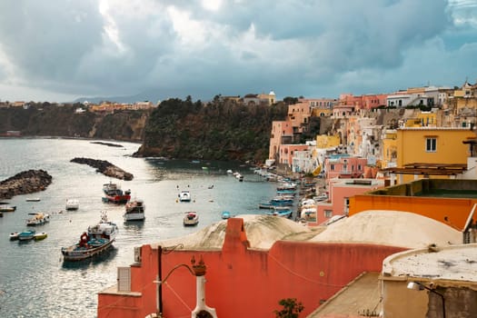 View of the Port of Corricella with lots of colorful houses on a sunny day in Procida Island, Italy.