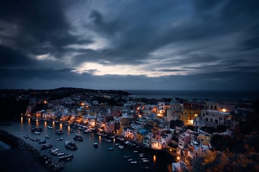 View of the Port of Corricella with lots of colorful houses after sunset in Procida Island, Italy.