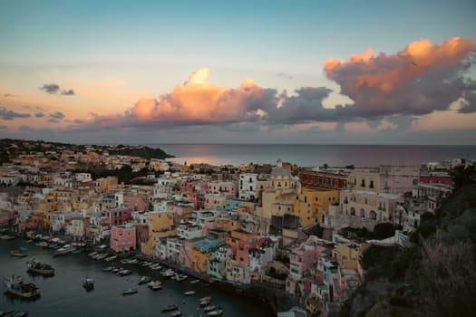 View of the Port of Corricella with lots of colorful houses in the sunset in Procida Island, Italy.