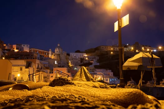 Fishing nets the Port of Corricella with lots of colorful houses after sunset in Procida Island, Italy.