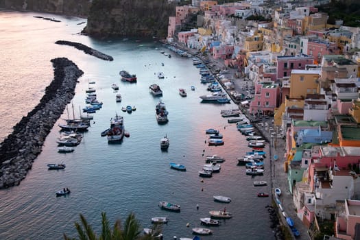 View of the Port of Corricella with lots of colorful houses in the sunset, Procida Island, Italy.