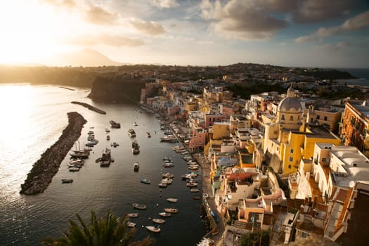 View of the Port of Corricella with lots of colorful houses in the sunset, Procida Island, Italy.