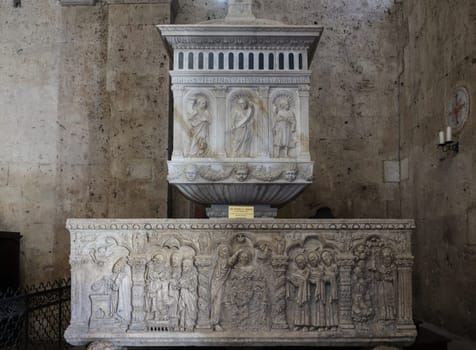 Massa Marittima, Italy - Sept 11, 2022:  Monumental baptismal font, with a rectangular bath surmounted by a small temple. The baptistery dates from 1267. Cathedral of Saint Cerbonius in Massa Marittima. Italy