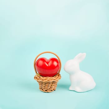 Wicker basket with a big red heart and an easter bunny, rabbit brings gift of love, greeting card for holiday