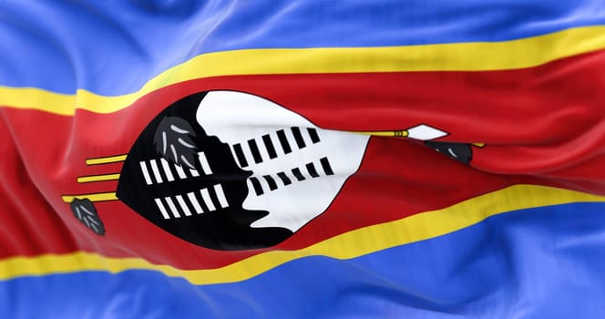 Eswatini national flag waving. The flag is blue, yellow, red stripes with black & white shield, staff and spears. Rippled fabric. Textured background. Selective focus. Realistic 3d illustration
