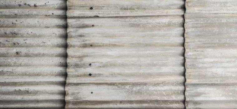 Wall protected with fibre cement corrugated sheets. Disused construction material for containing elements harmful to human health