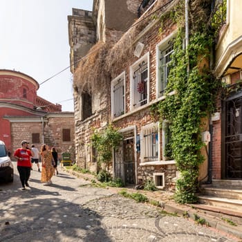 Istanbul, Turkey - August 28, 2022: Cobblestone alley with beautiful old traditional red bricks houses in old Balat district, on a summer day