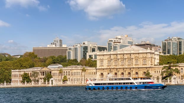 Ferry boat passing by Dolmabahce Palace, in Besiktas district of Istanbul, Turkey, on the European coast of the Bosporus strait, main administrative center of the Ottoman Empire formerly
