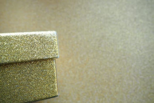 Golden gift box on a golden background. Decorative surprise box. Copy space.