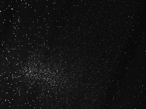 Black bokeh texture on black background. White glitter or illuminated dust.