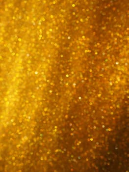 Bokeh light of gold glitters. Golden glitter texture background. Sparkling glitter wrapping paper with sequins and sparkles. Festive golden bokeh and glitter. Diagonal stripes and waves.