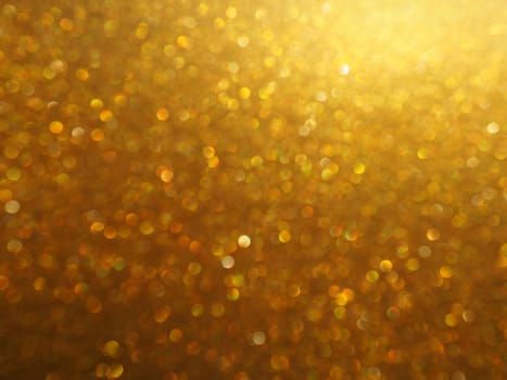 Bokeh light of gold glitters. Golden glitter texture background. Sparkling glitter wrapping paper with sequins and sparkles. Festive golden bokeh and glitter. Beautiful background