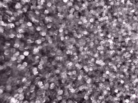 Bokeh light of white glitters. Black grey white silver glitter texture background. Sparkling glitter wrapping paper with sequins and sparkles. Festive bokeh and glitter. Purple tint.