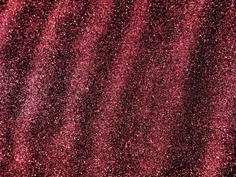 Bokeh light of pink glitters on black background. Magenta glitter texture. Sparkling glitter wrapping paper with sequins and sparkles. Festive purple bokeh and glitter. Diagonal stripes and waves.