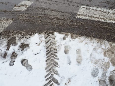 A fork or siding from a roundabout. Snowdrifts on the side of the road. Bad traffic weather. Footprints in the snow. Difficult driving conditions. Winter slosh on the road. Braking distance of a car