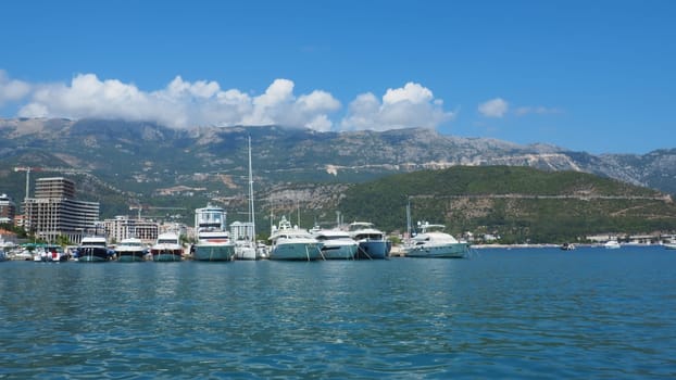 Budva, Montenegro, August 15 2022 Adriatic sea, coast, mountains, sea ripples. Boats and ships are moored to the embankment. Water transport parking. Summer resort trips with tourist water activities.