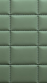 The surface texture of artificial leather in pistachio color, stitched in the form of rhombuses, squares, rectangles. Quilted eco-leather.